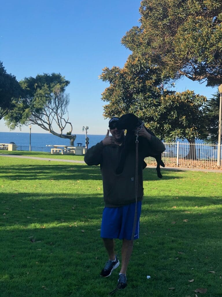 A man standing in the grass holding onto a rope.